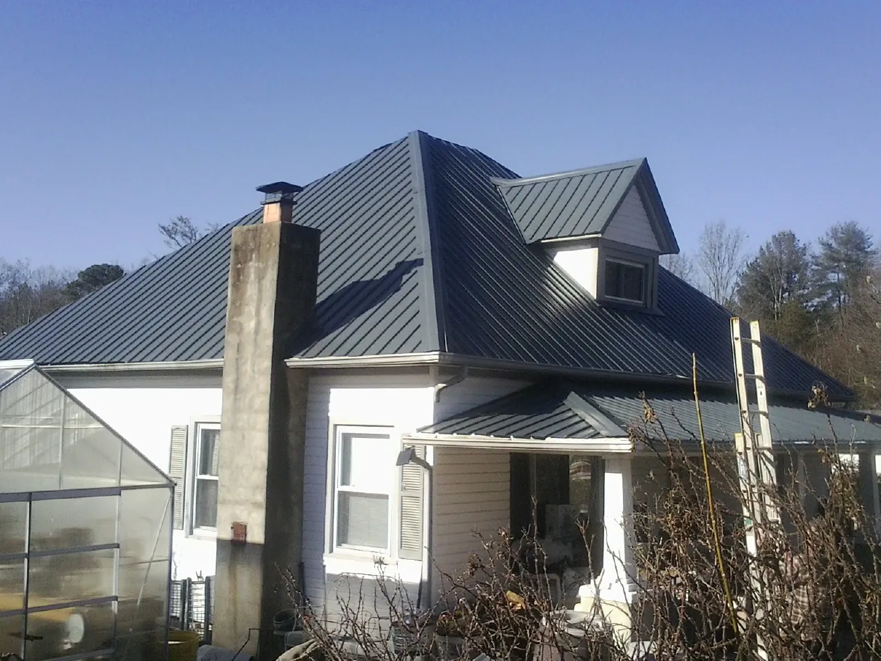 Dark blue standing seam metal roof on a white farmhouse with dormer — Slate & Tile Roof Repair by Roofing Brothers in Pomaria