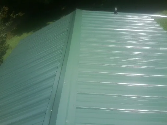New green metal panels meeting at the ridge of a roof — Flat Roof Repair work by our crew in Pomaria