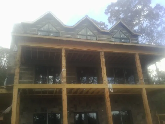 Dormers and porch framing on a large log home under construction — Roof Coating work by our crew in Pomaria
