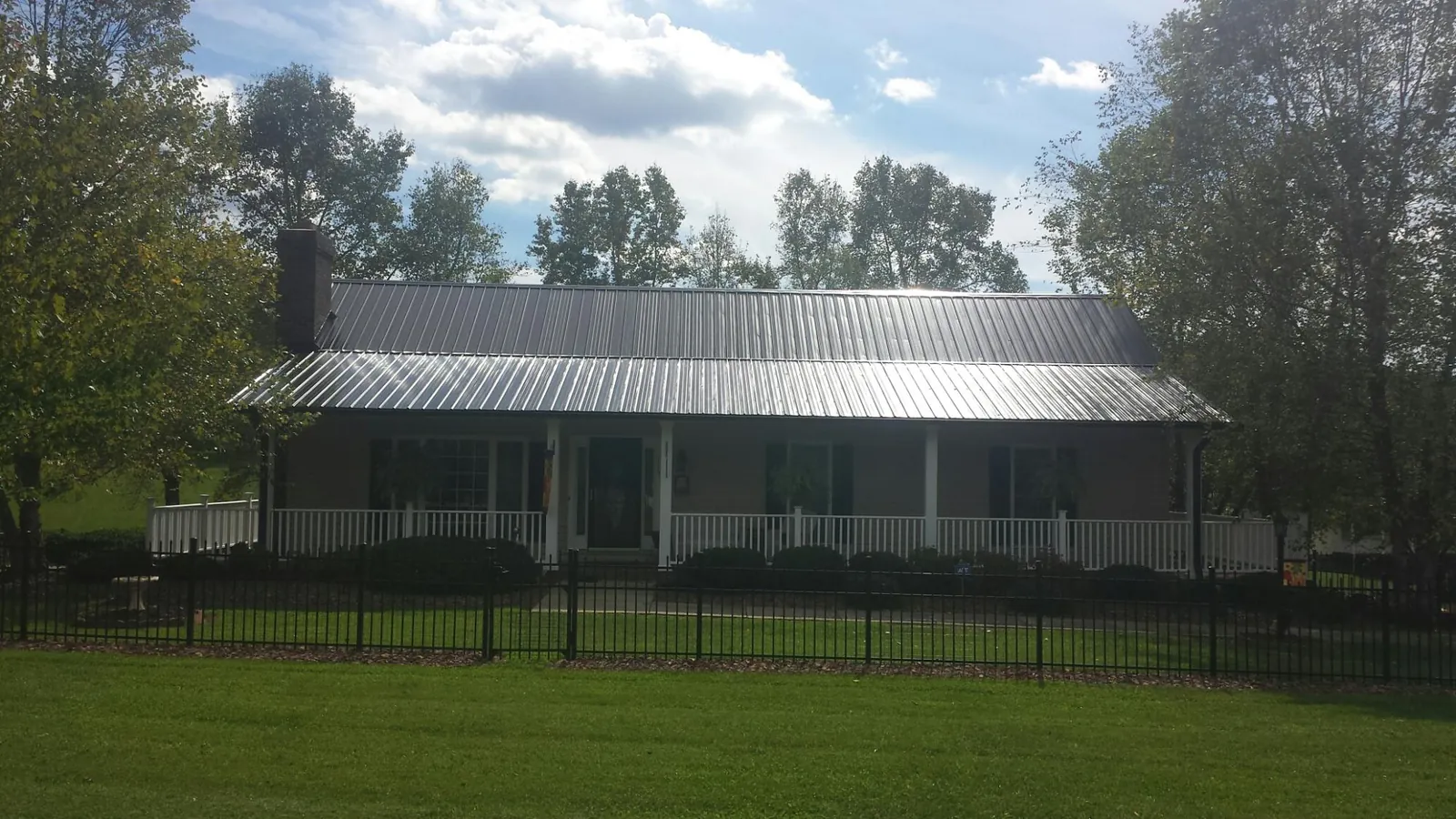 Gray metal roof on a brick ranch with a full width front porch — Gutter Guard Installation work by our crew in Pomaria
