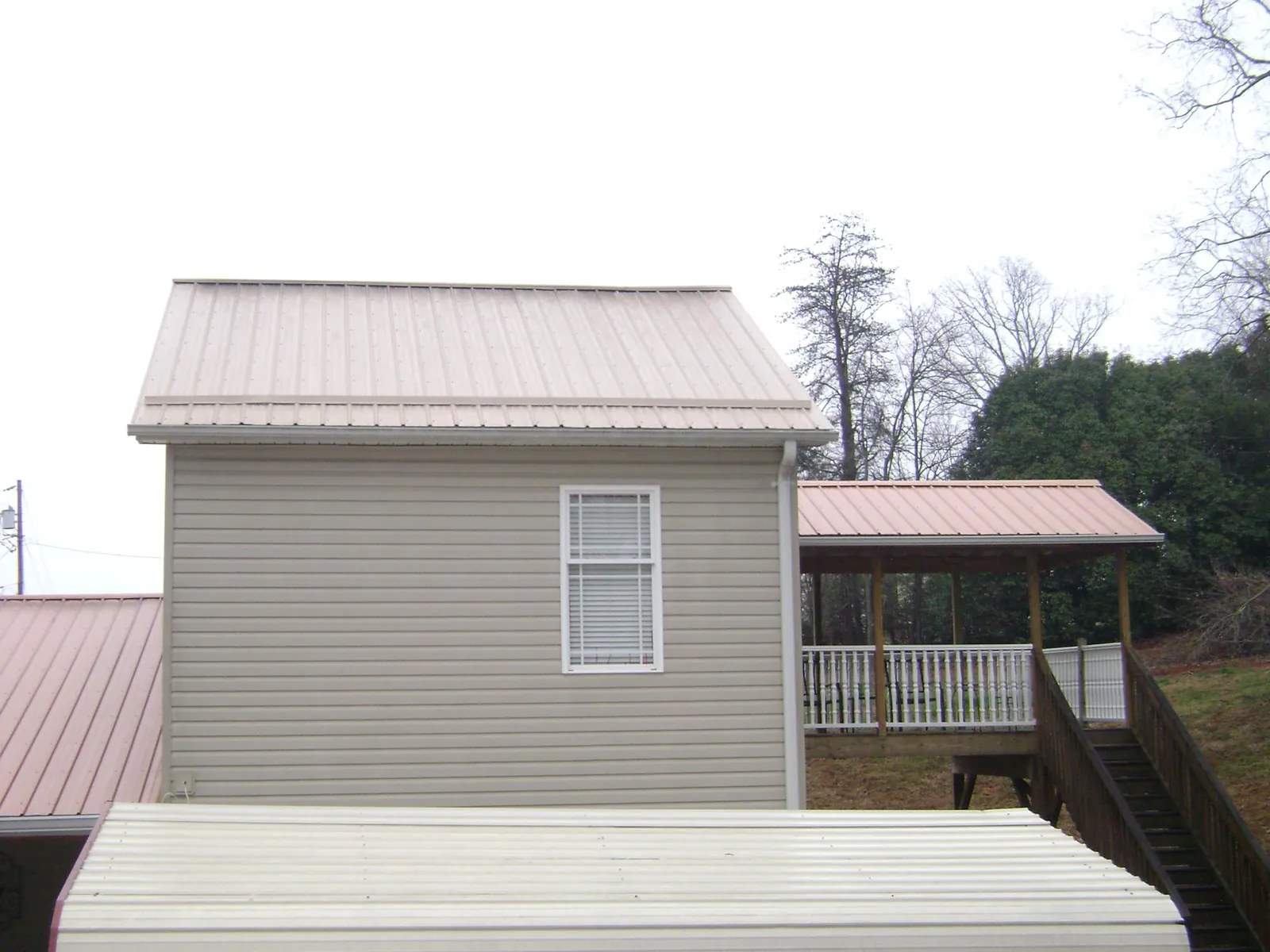 Tan metal roofs on a two story addition and attached porch, from a Roof Replacement job in Pomaria