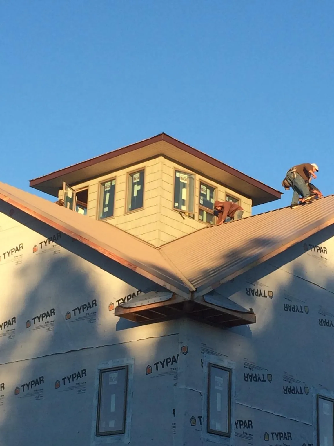 Roofers working around a rooftop cupola on a new metal roof at sunset — Roof Waterproofing in Pomaria by Roofing Brothers